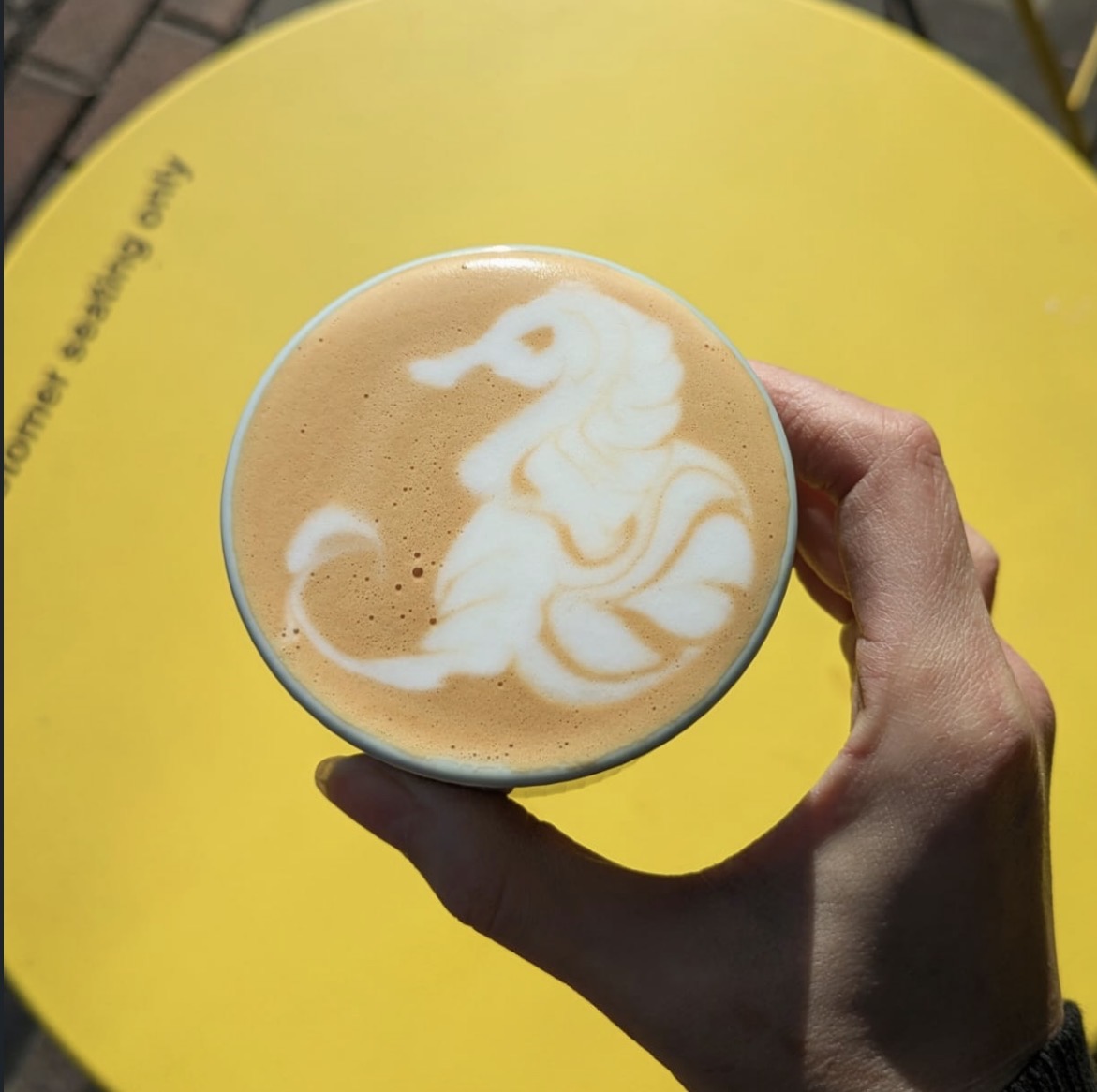 Latte art on a yellow table outside Ocha